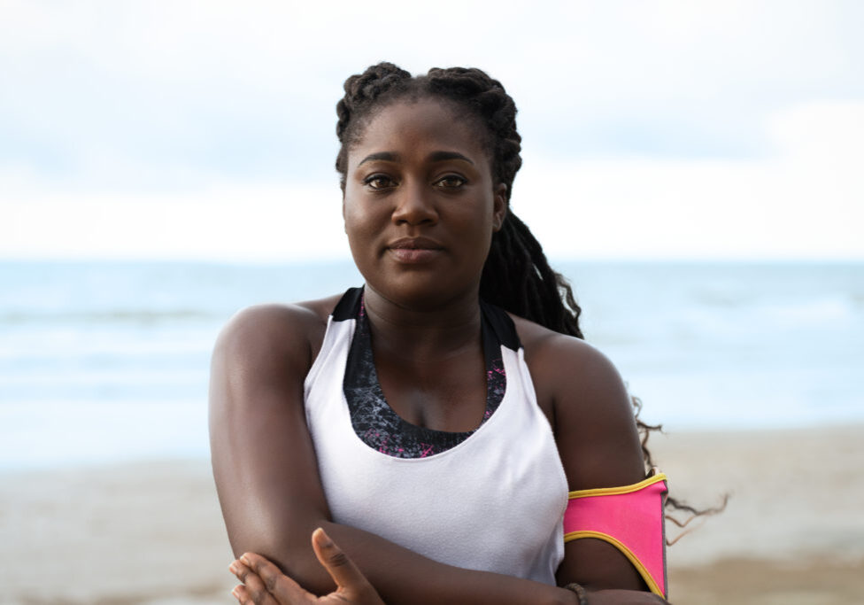 Portrait of sporty attractive african woman doing exercises on the beach outdoor
